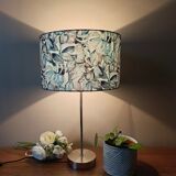 Table lamp with chrome stem, tropical plant shade.