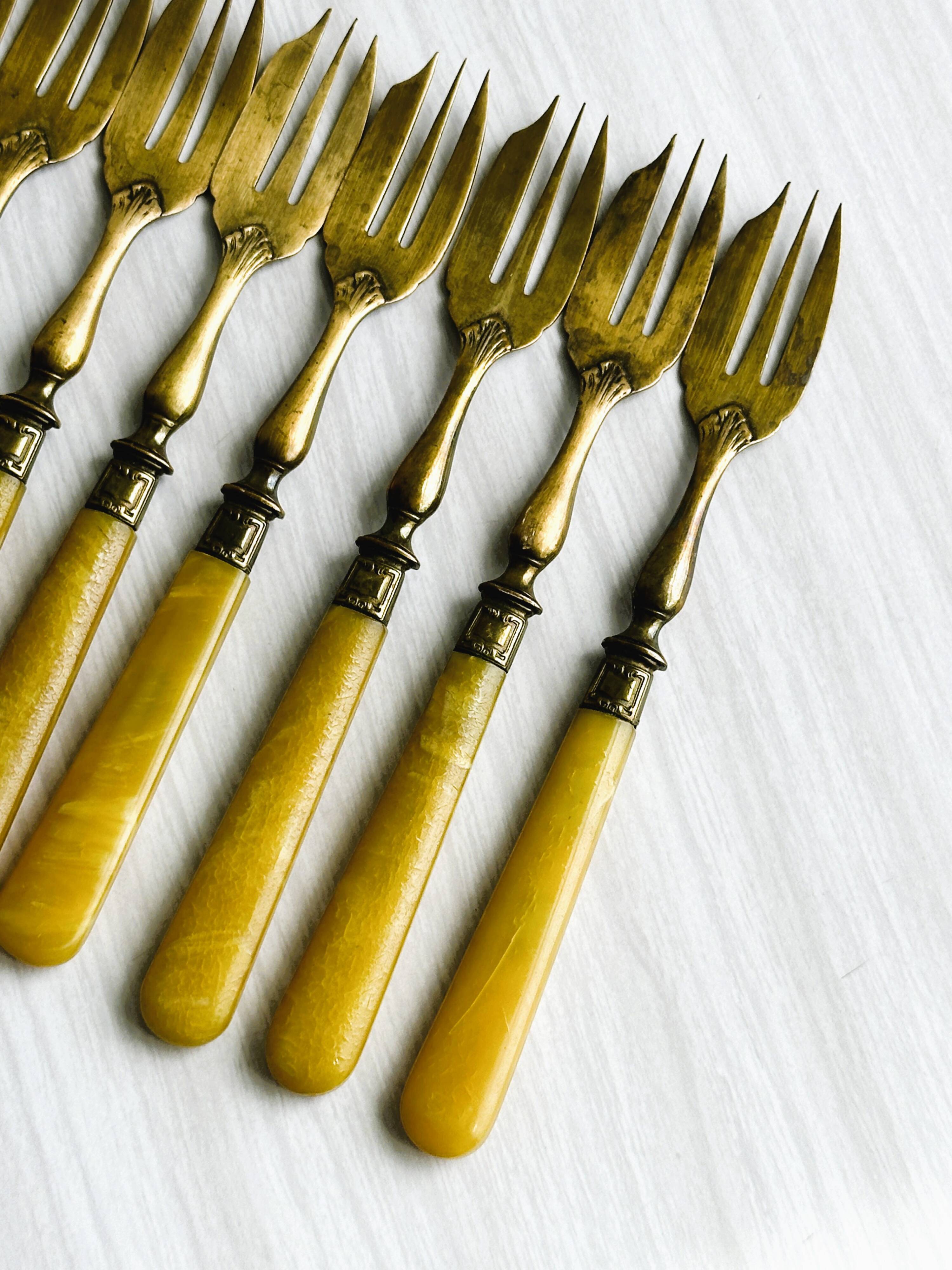 8 fourchettes à dessert vintage en métal doré et  manches en bakélite jaune.