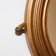 Beveled oval mirror in gilded wood