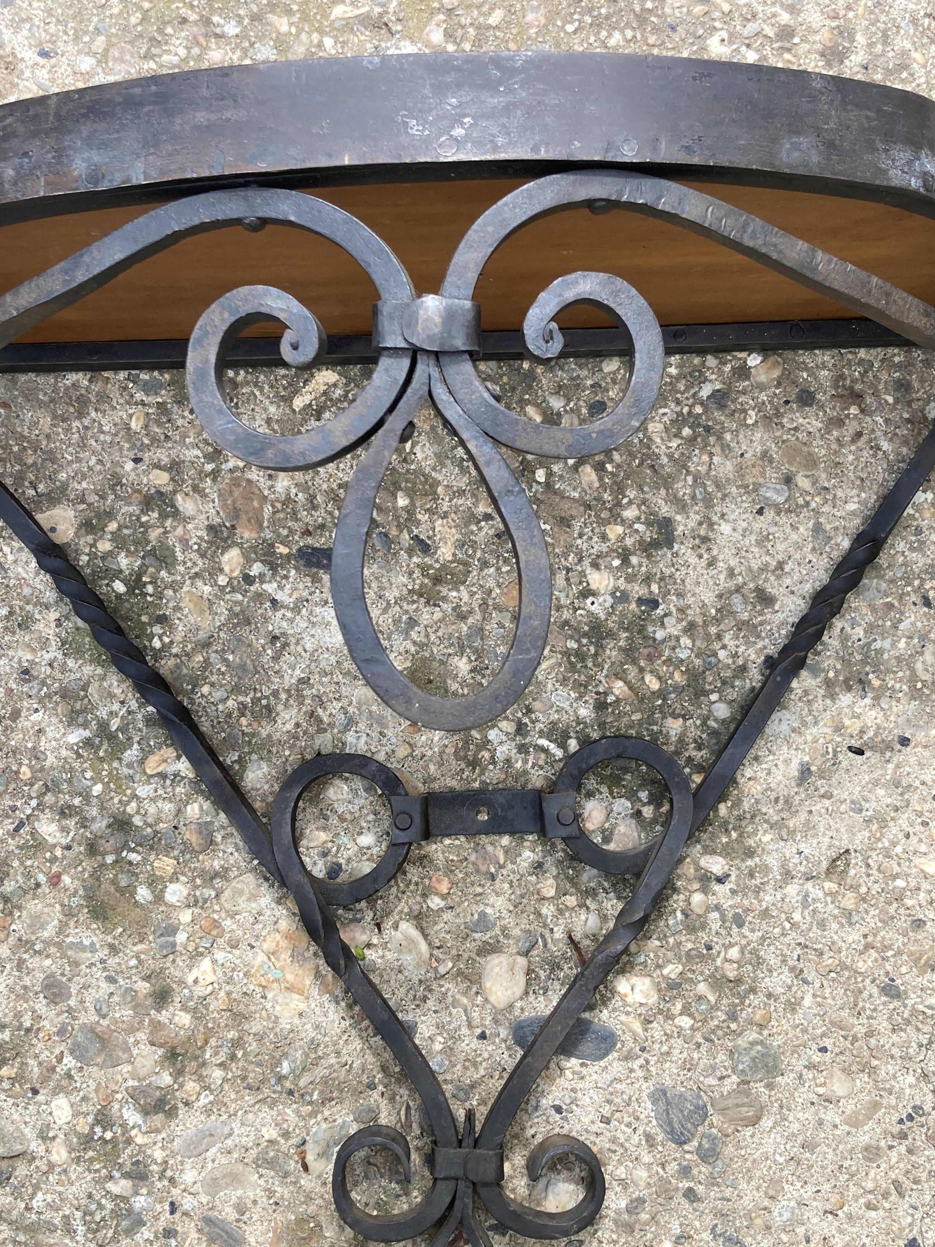 Old wrought iron console with a fleur-de-lis design.