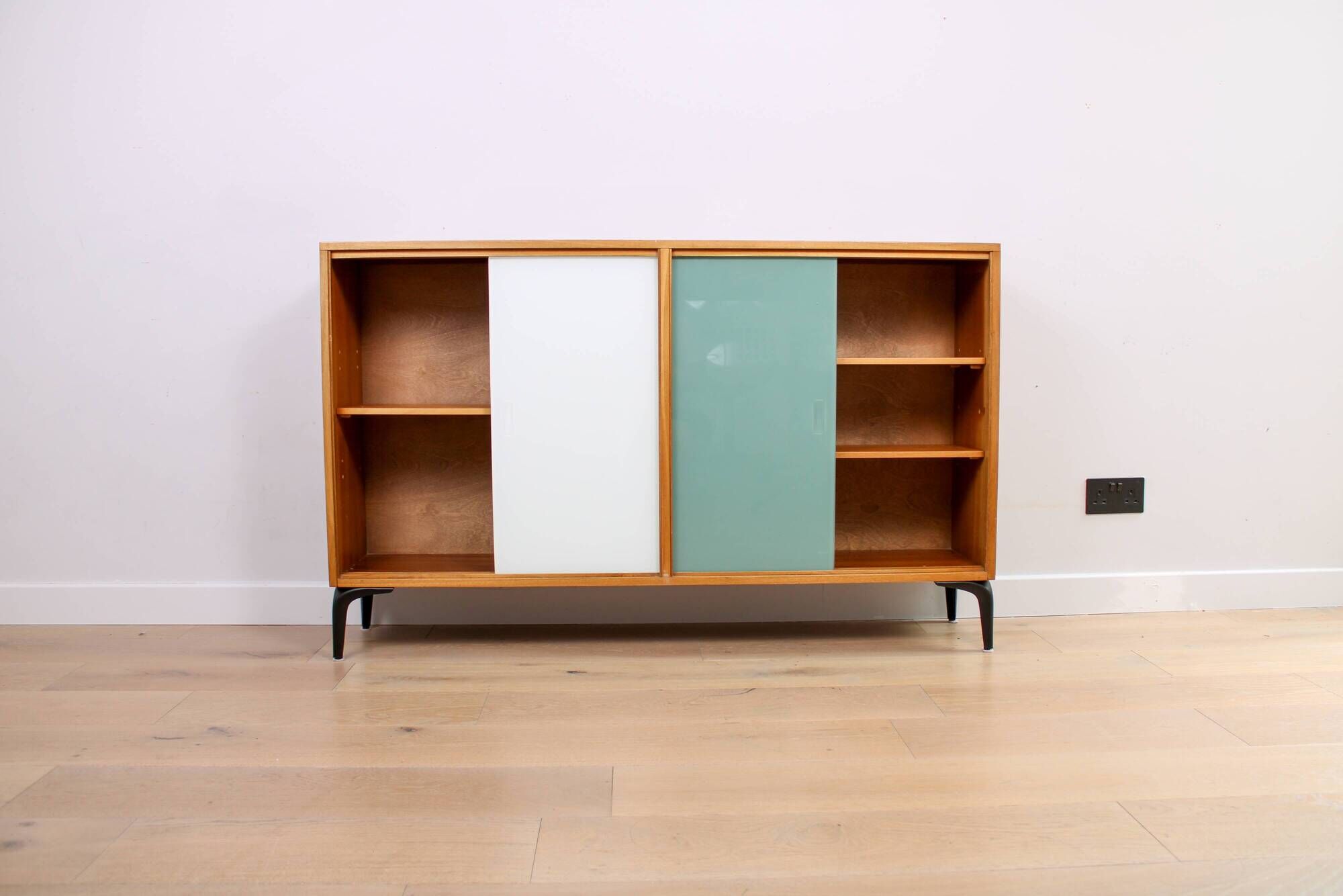A vintage mid-century bookshelf/sideboard with green and white sliding door