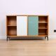 A vintage mid-century bookshelf/sideboard with green and white sliding door