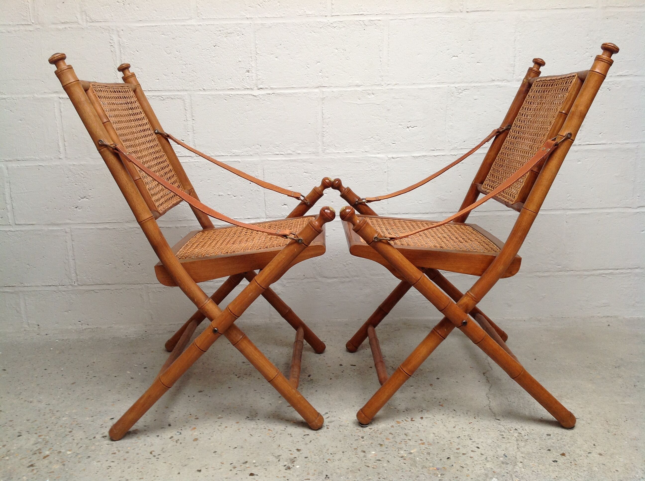 Pair of folding chairs in bamboo and caning, leather and brass