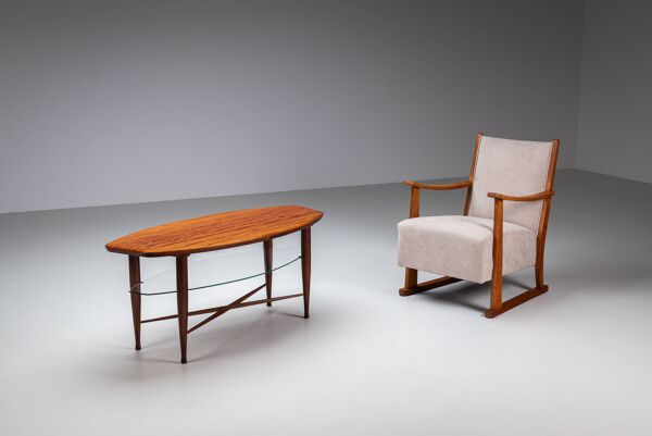 Table basse asymétrique avec rangement en verre et détails de pieds en croix.
