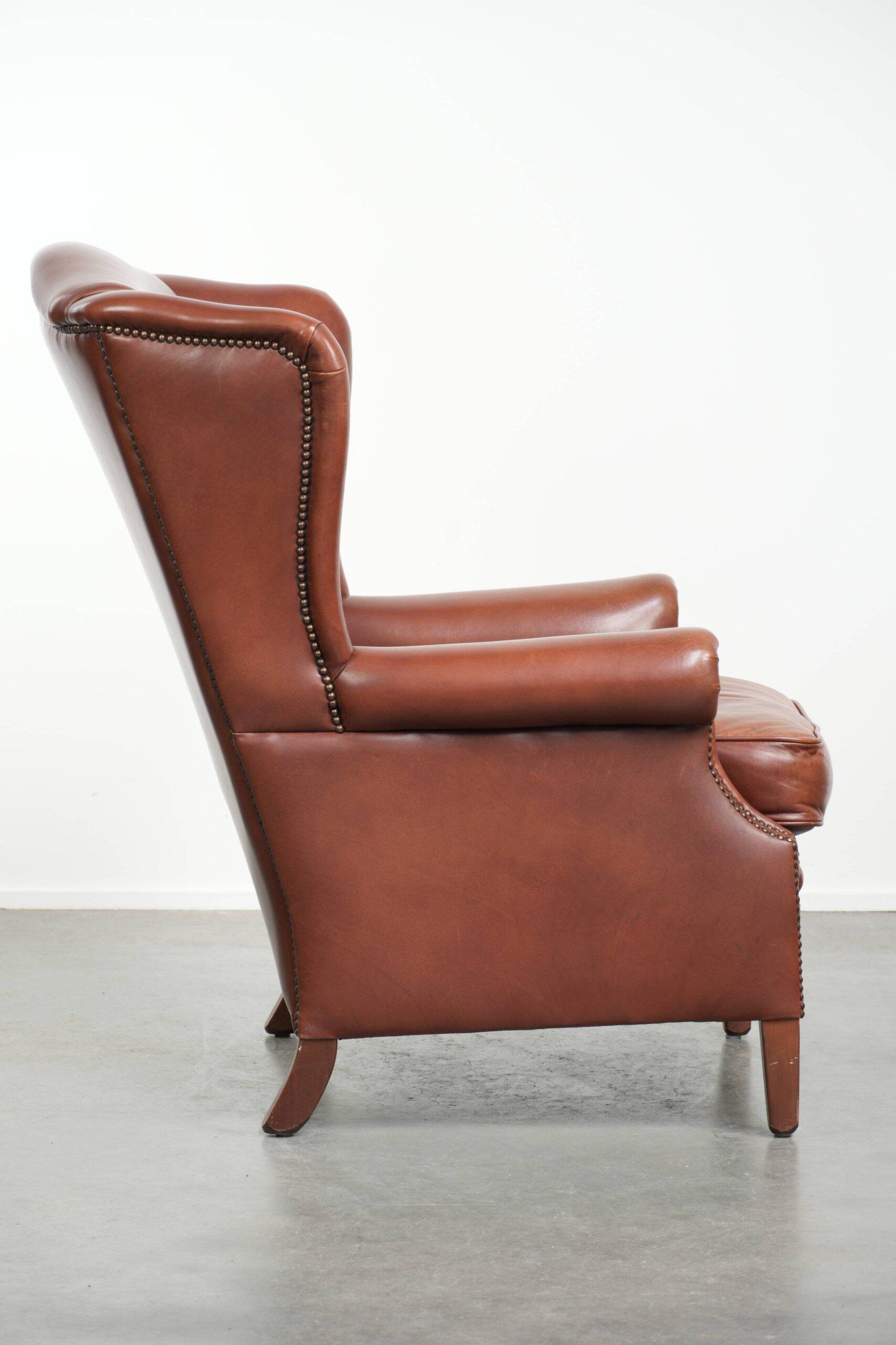 Cognac-coloured cow leather wingback armchair in English style