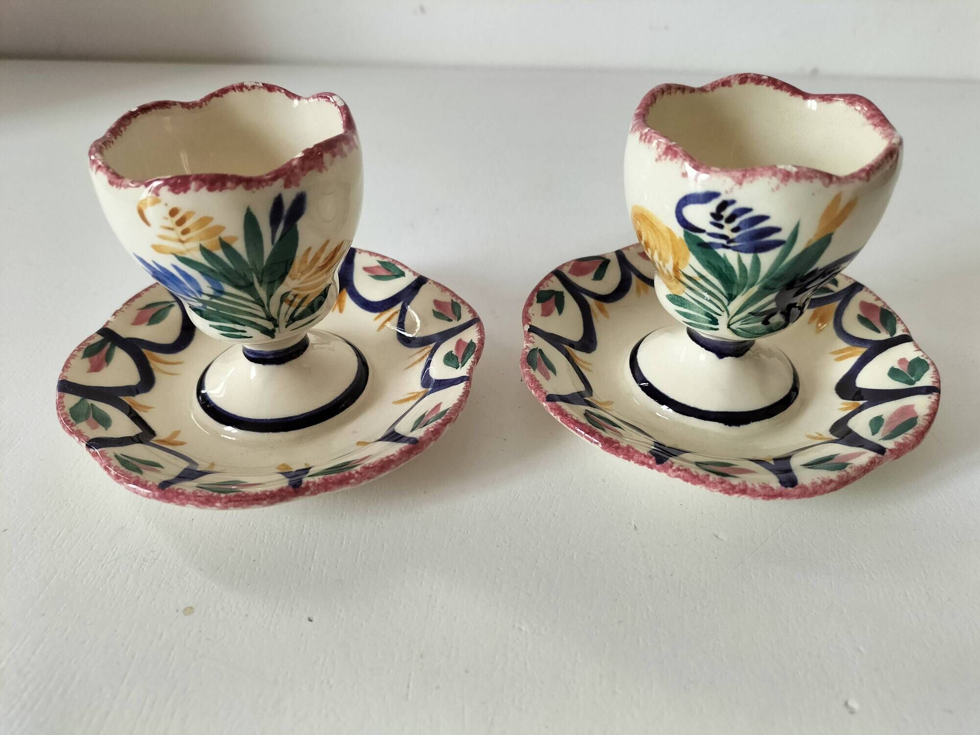 Pair of HB Quimper egg cups with integrated pedestal base, floral decoration