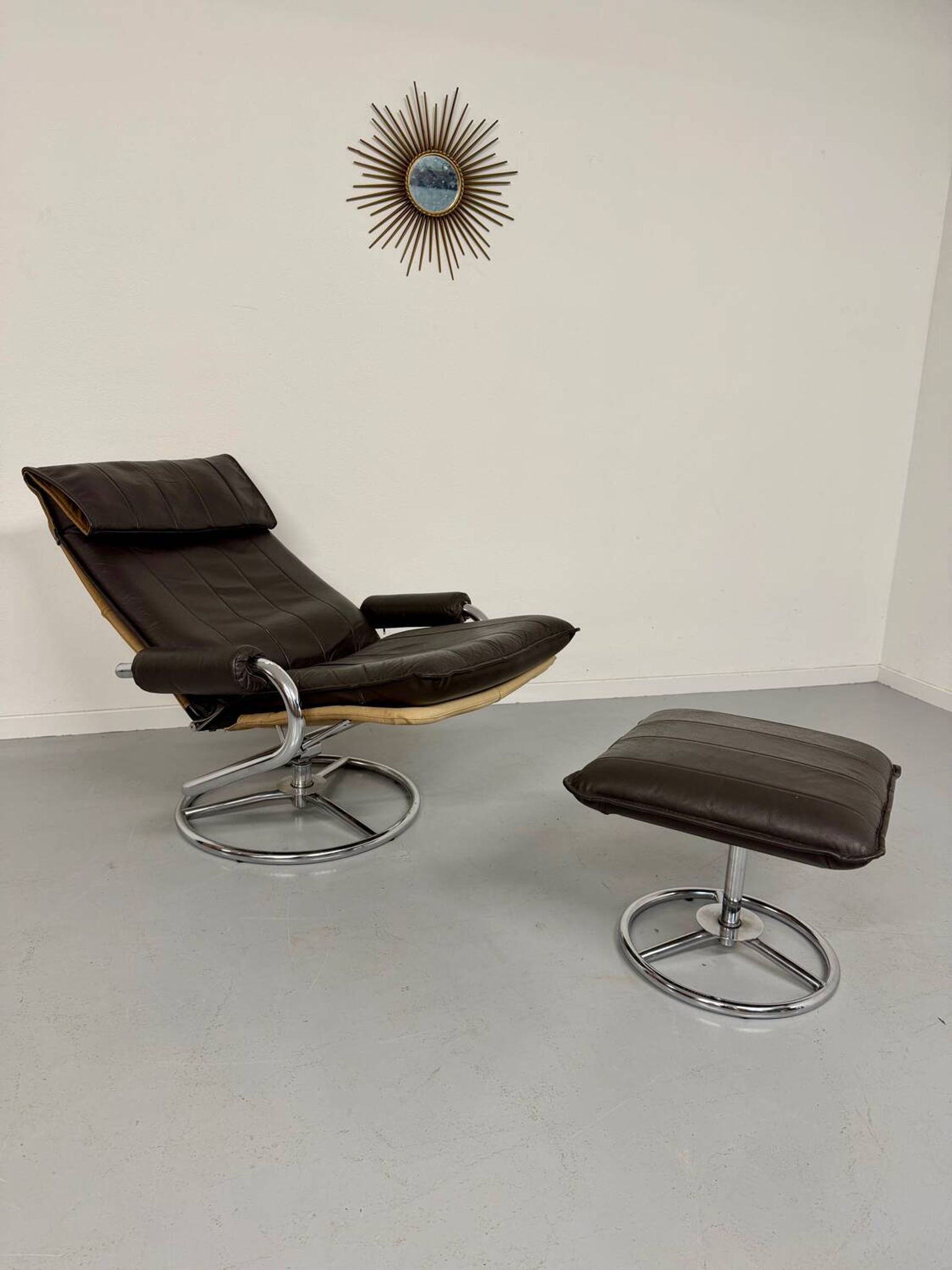 Vintage leather reclining armchair and its 1970s designer ottoman.