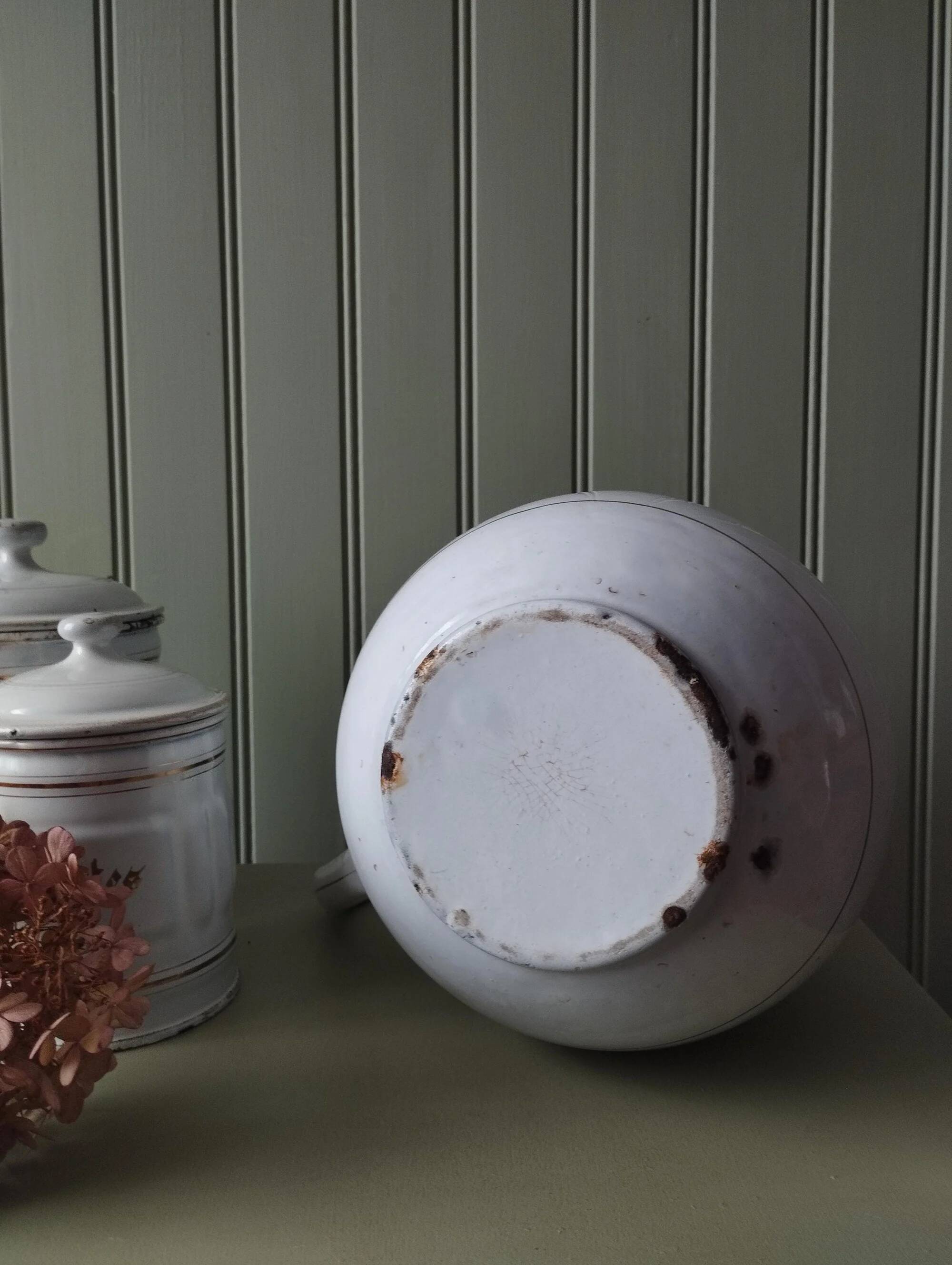 Old enamelled metal jug with gold trim.