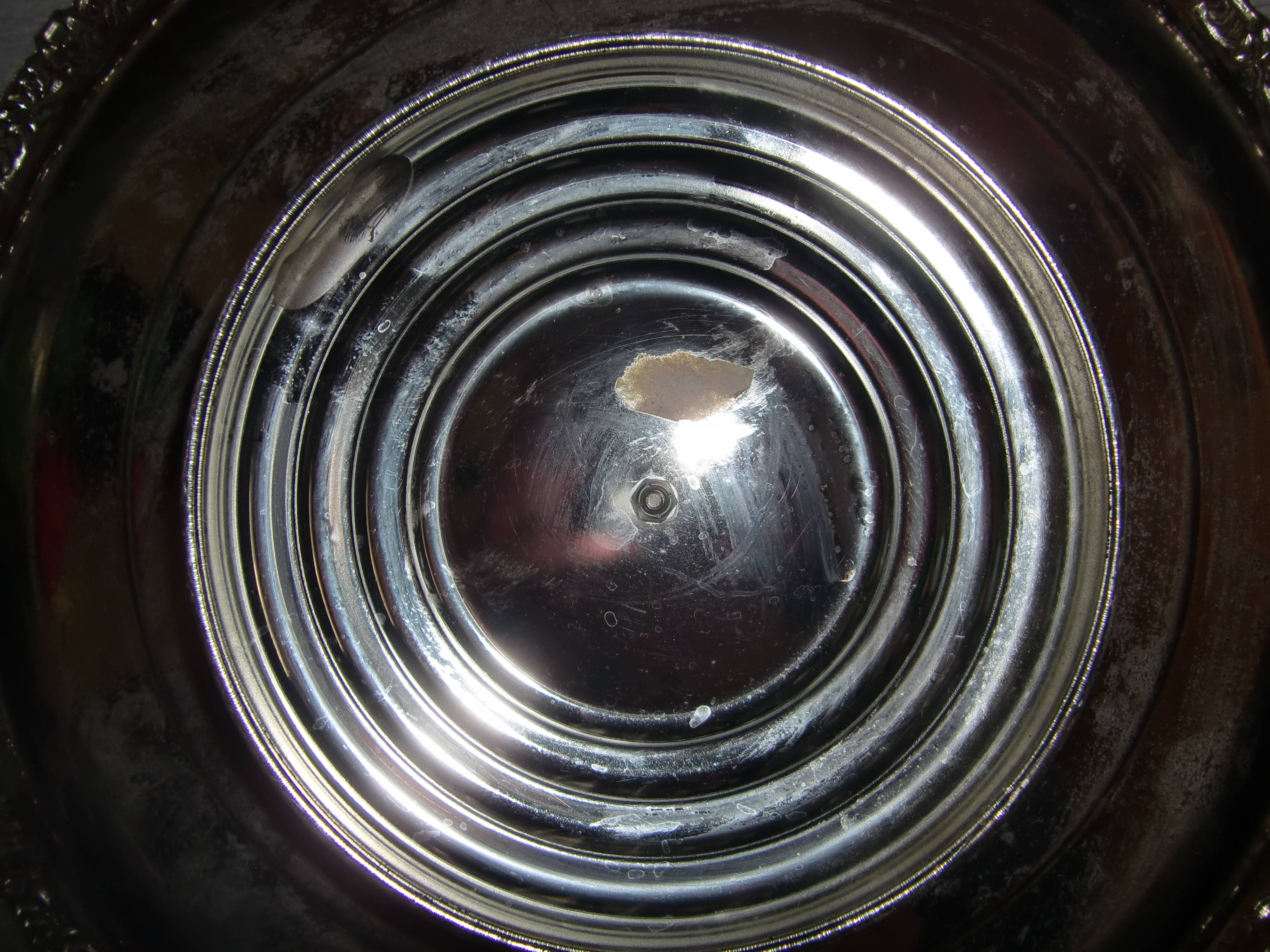 Large silver metal tray raised by a central foot