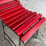 Red slatted chair with a black metal frame.