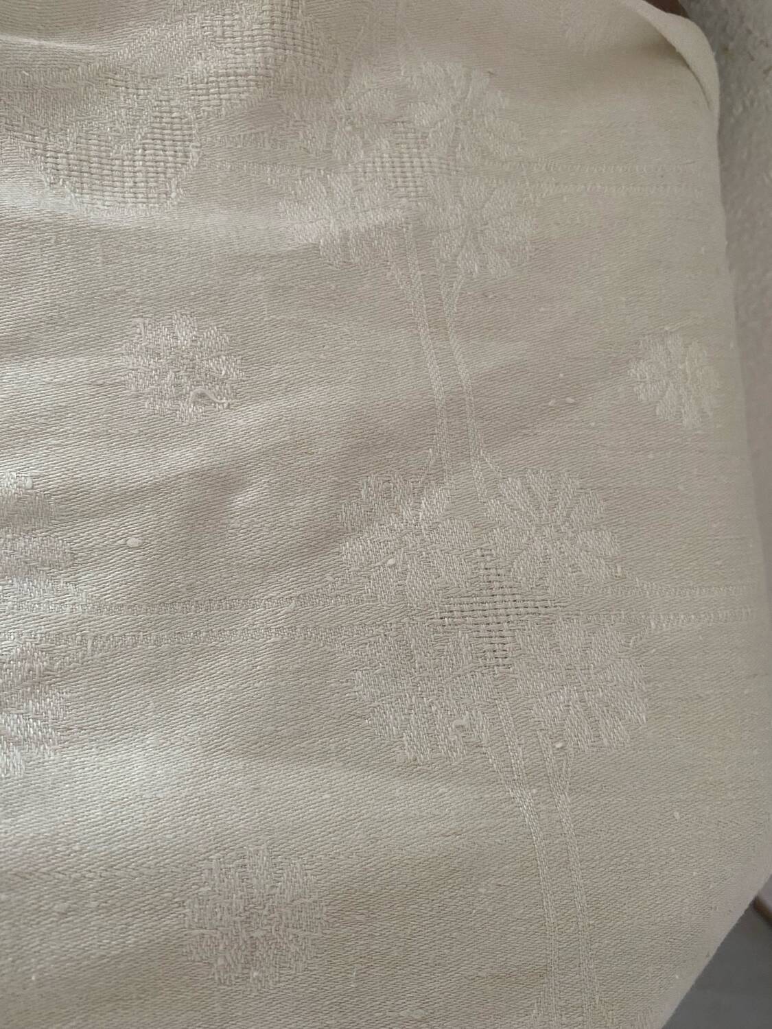 Damask tablecloth with a floral pattern and a central embroidered monogram.