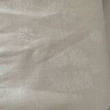 Damask tablecloth with a floral pattern and a central embroidered monogram.