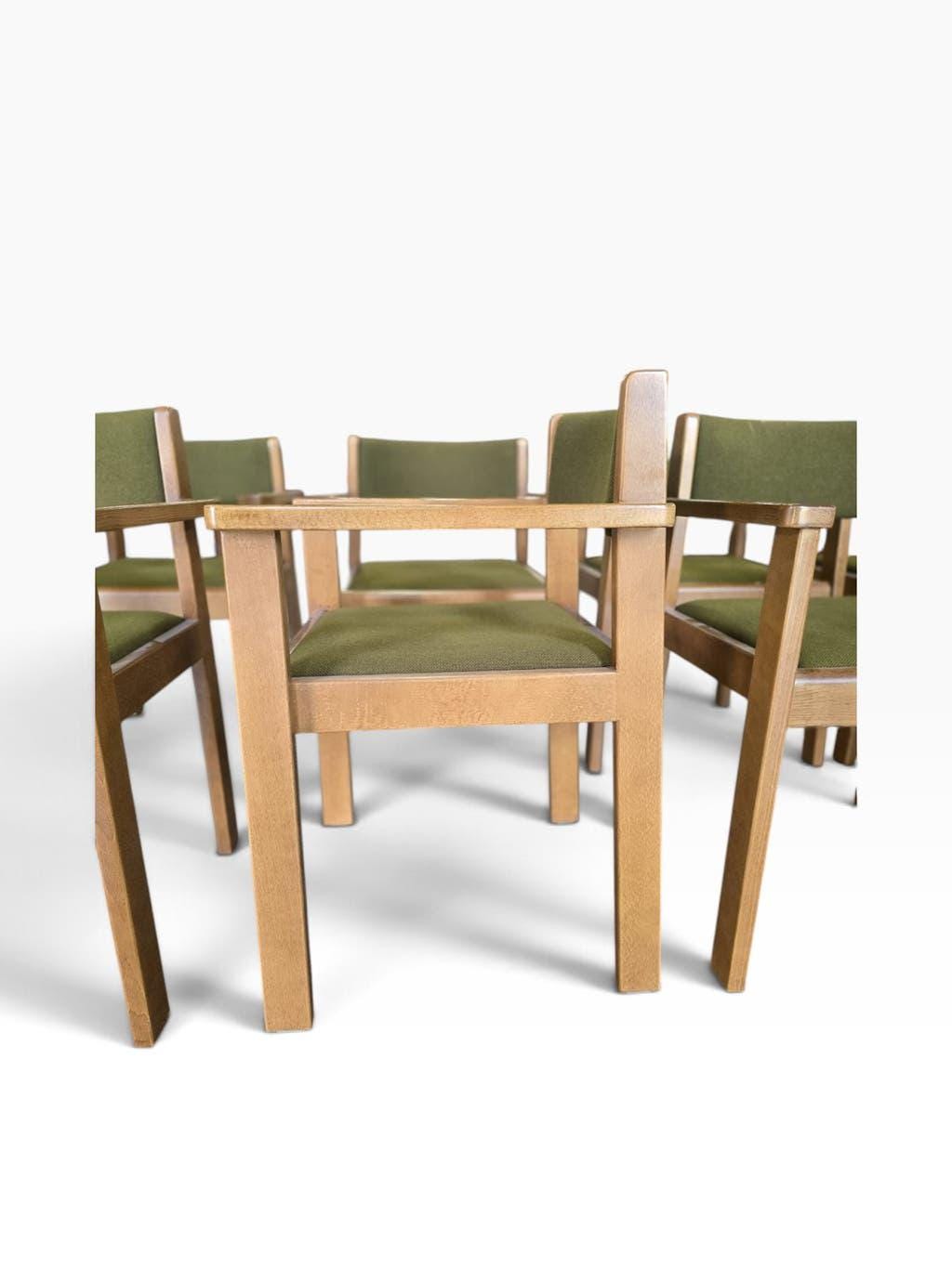 Vintage wooden chair with olive green seat and armrests.