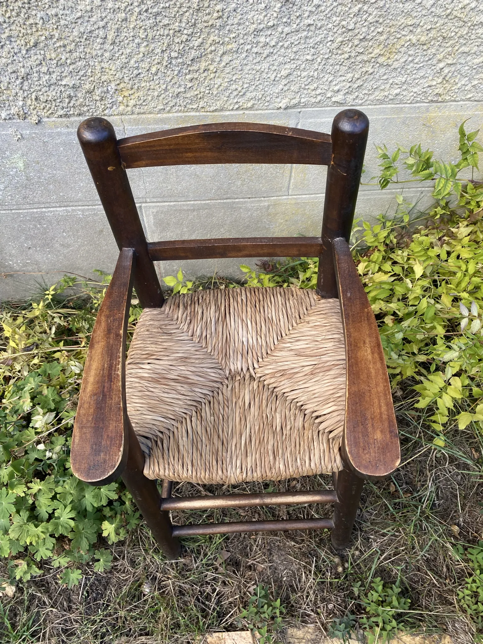 Vintage wooden children's high chair with straw.