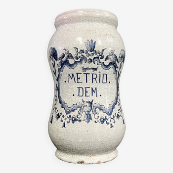 Terracotta medicine jar with blue decorations on a white background bearing the inscription Metrid Dem