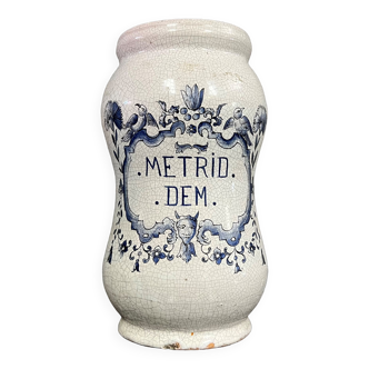 Terracotta medicine jar with blue decorations on a white background bearing the inscription Metrid Dem