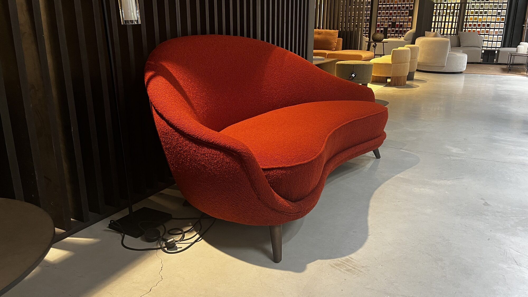 Two-seater sofa in red/orange boucle fabric.
