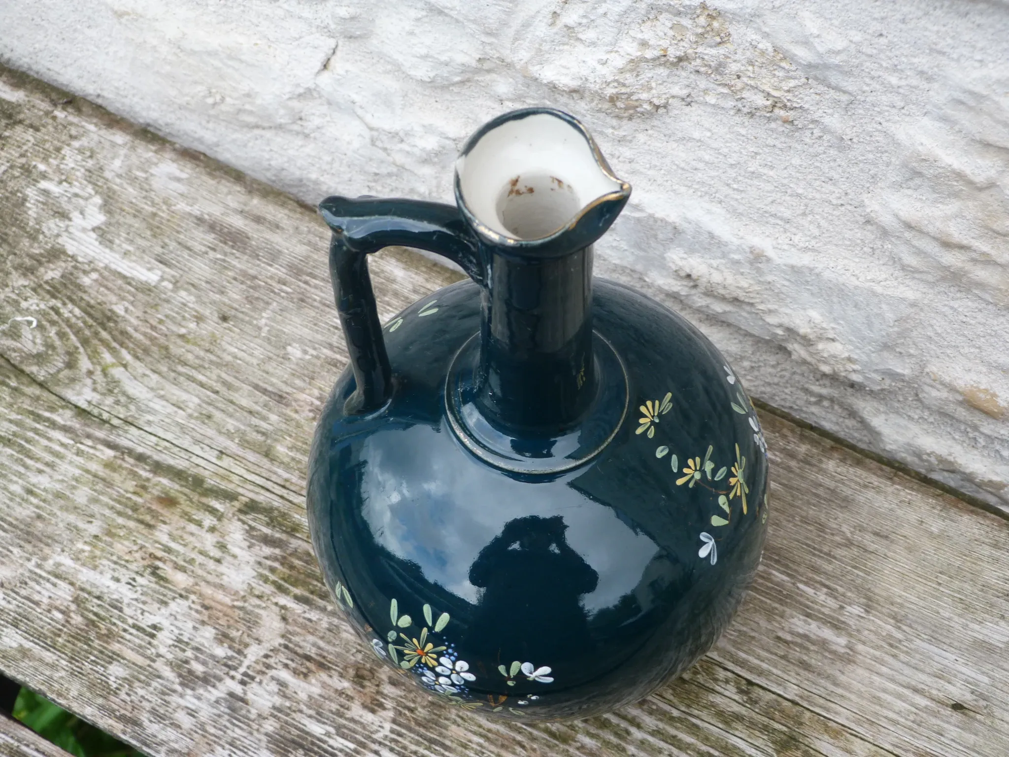 Old ceramic jug with flowers or single-stem vase.