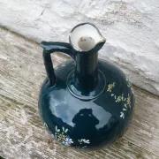 Old ceramic jug with flowers or single-stem vase.