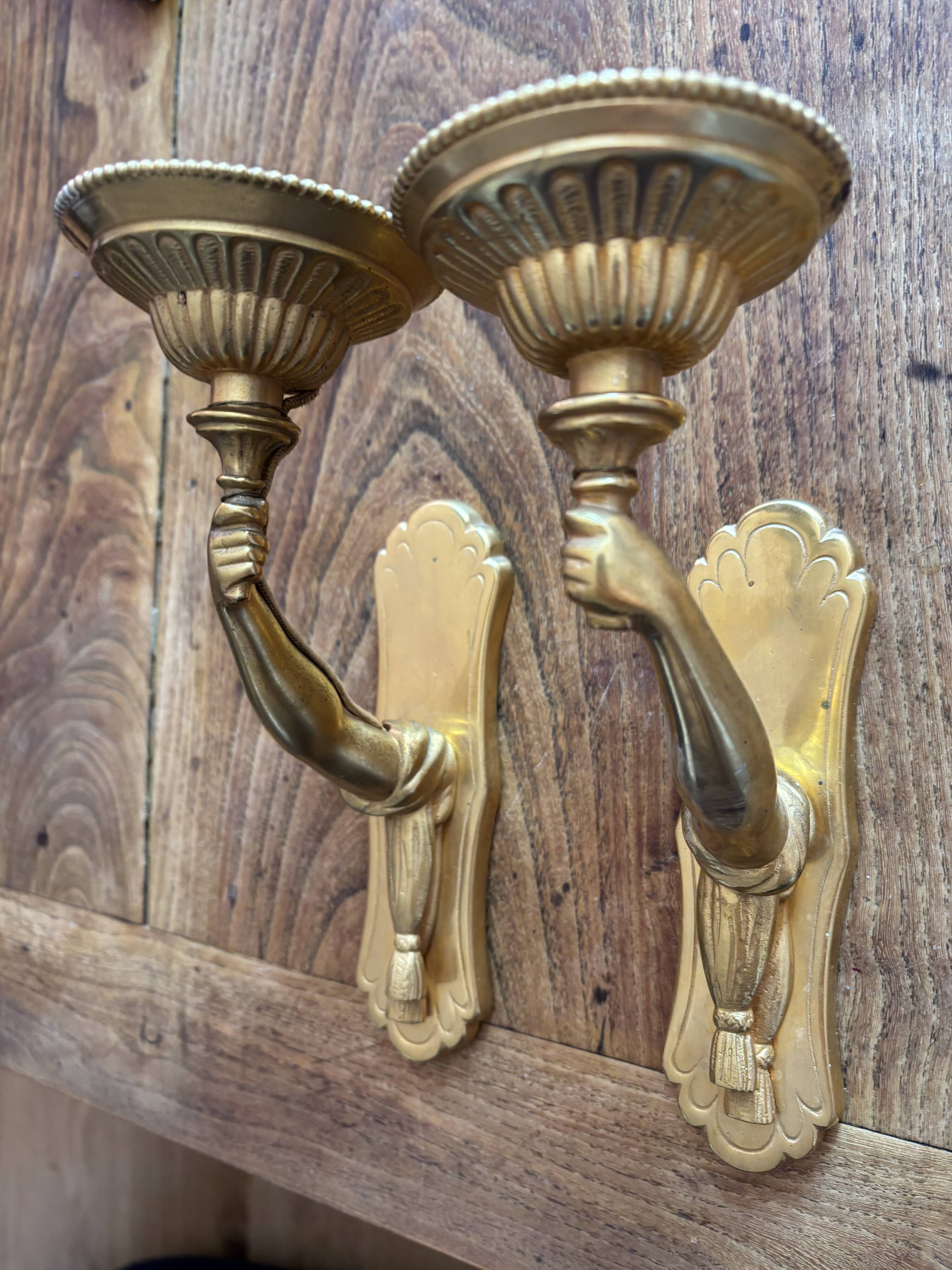 Pair of bronze wall sconces with outstretched arms and hands