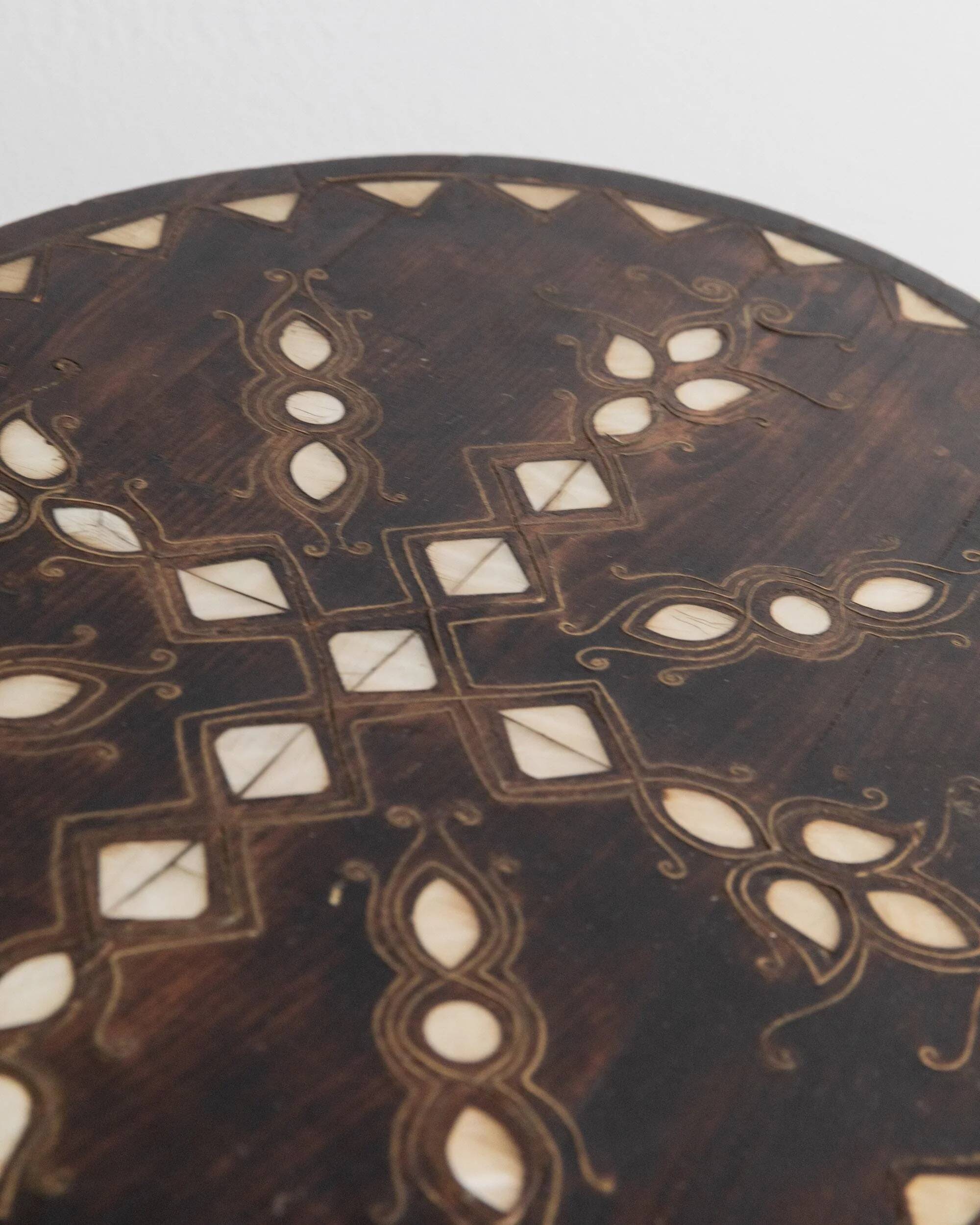 Vintage side table from the early 19th century, dark wood with mother-of-pearl inlays, oval shape with three legs, ethnic style.