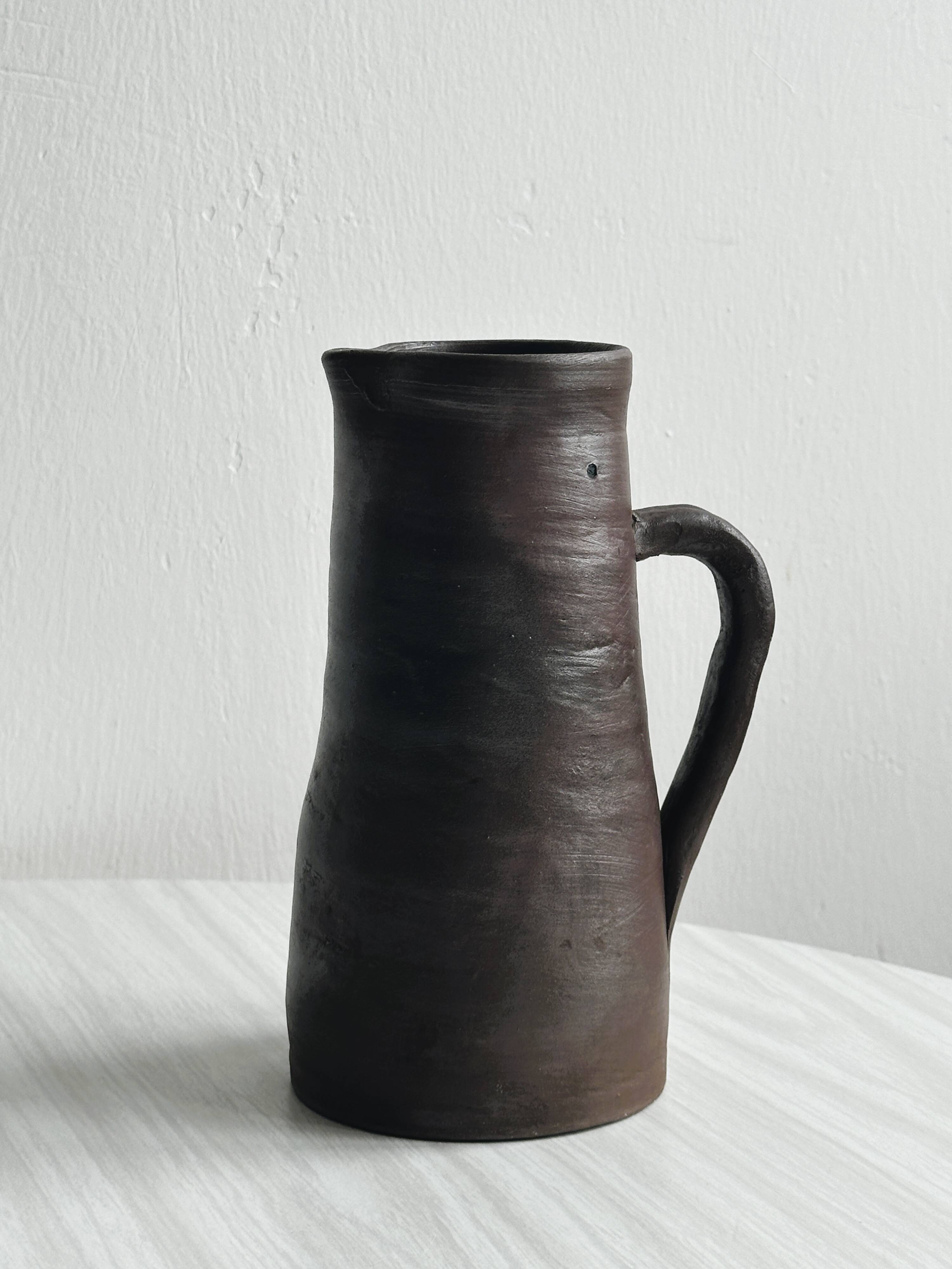 Pitcher, watering can in dark brown ceramic with matte finish.