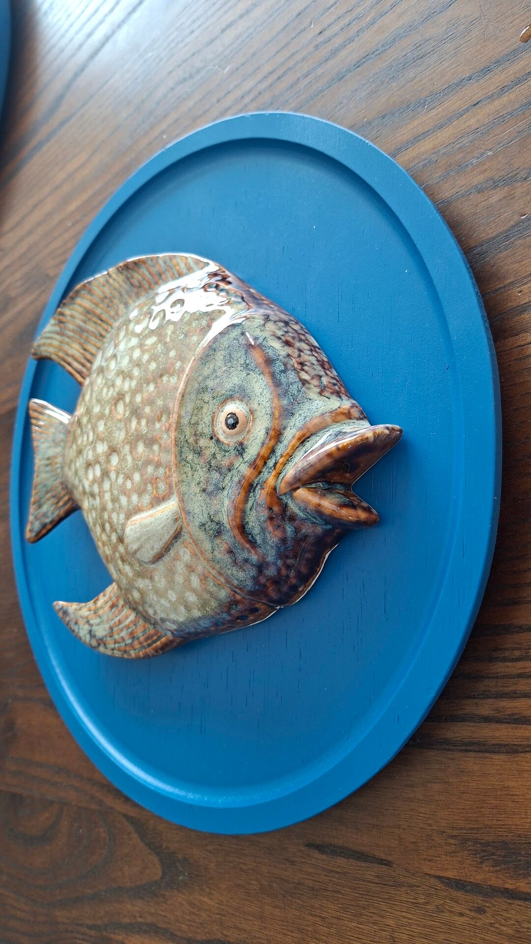 Vallauris ceramic wall sculpture of a relief fish on a blue plaque.