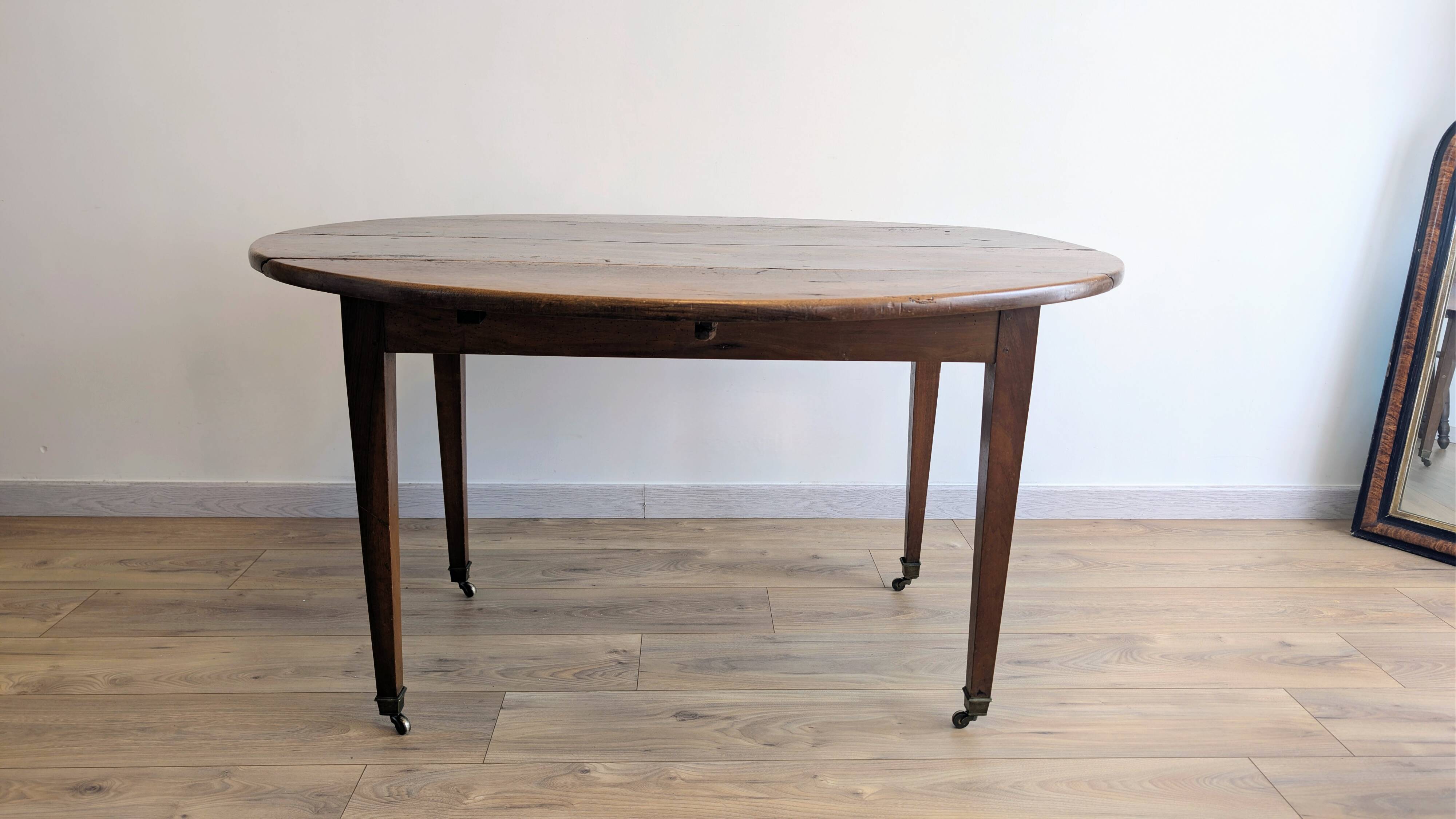 Antique wooden folding table with a patina and brass wheels.