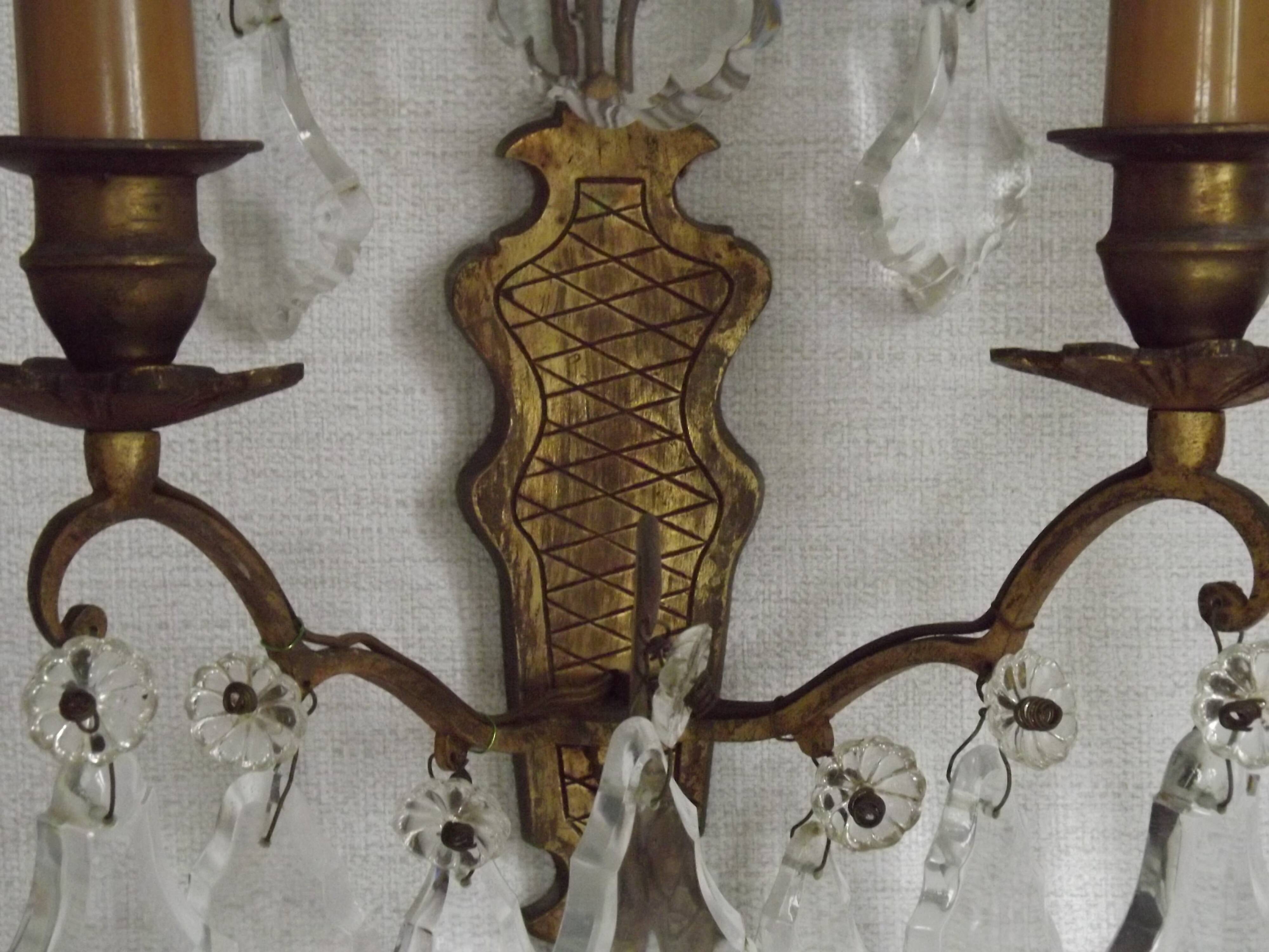 Pair of French antique brass double wall lights with assorted crystals.