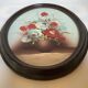 Oval painting of a bouquet of flowers, oil on panel.