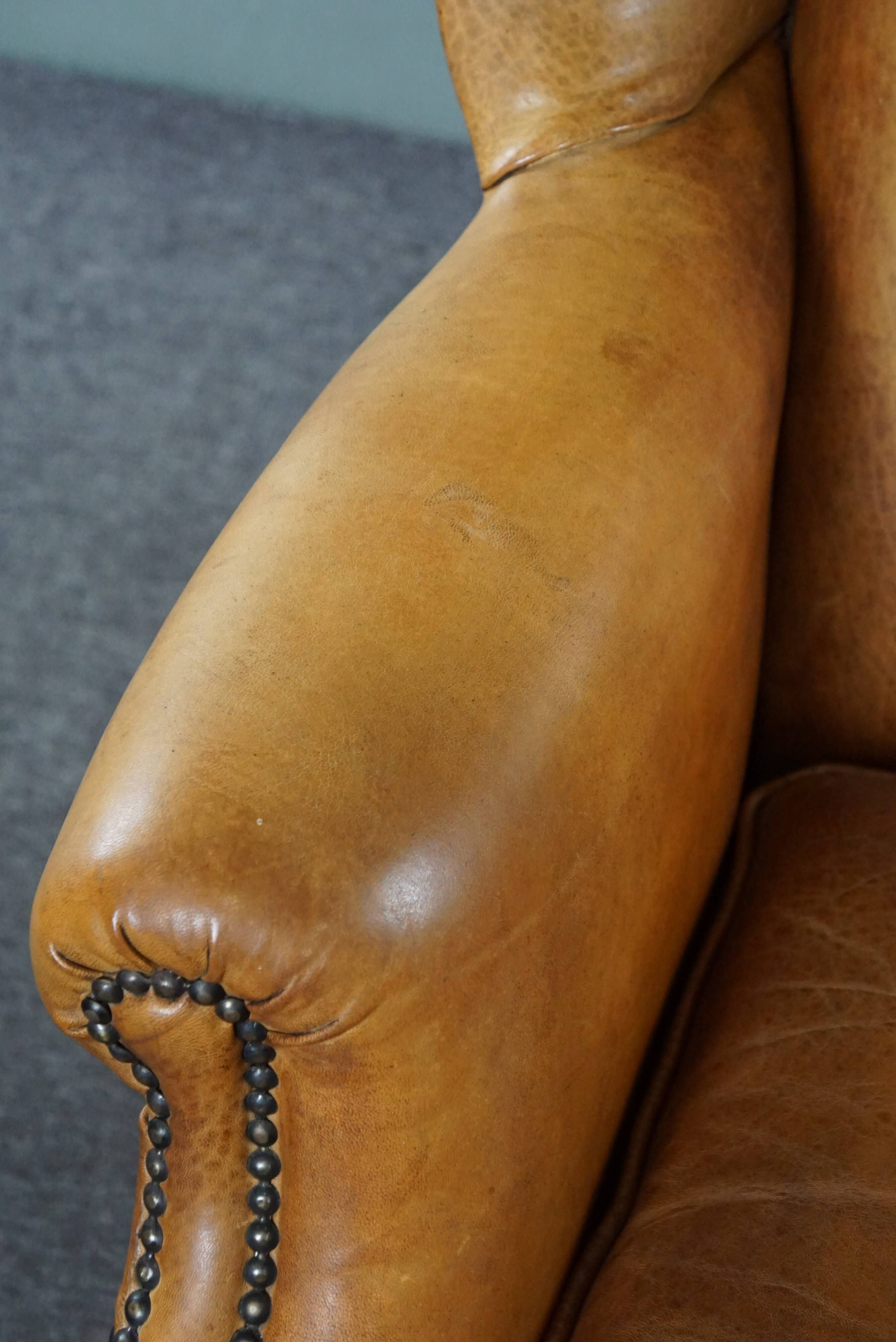 Old wingback armchair made of sheep leather in a correct condition