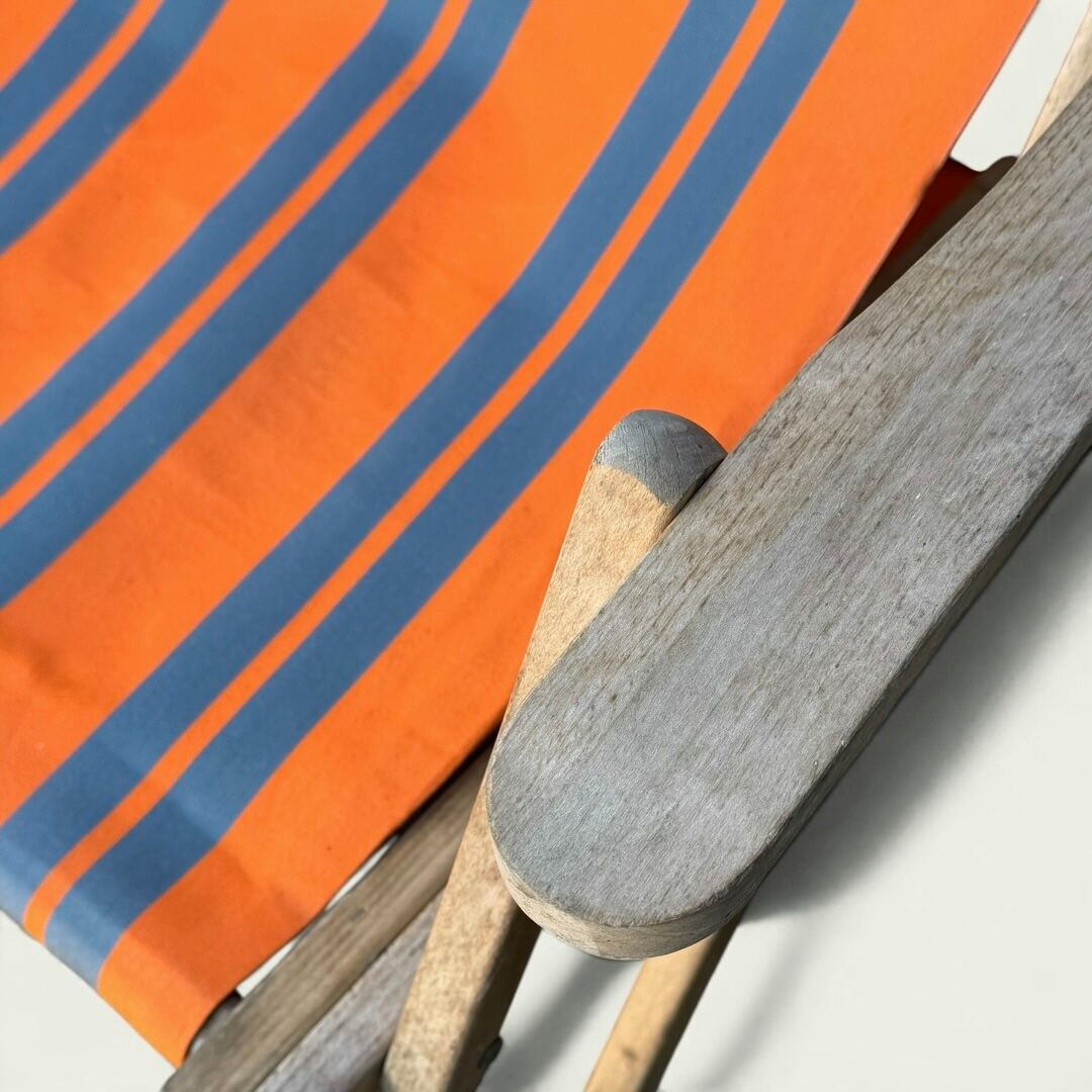 Vintage deck chair with orange and grey striped fabric, original patina.