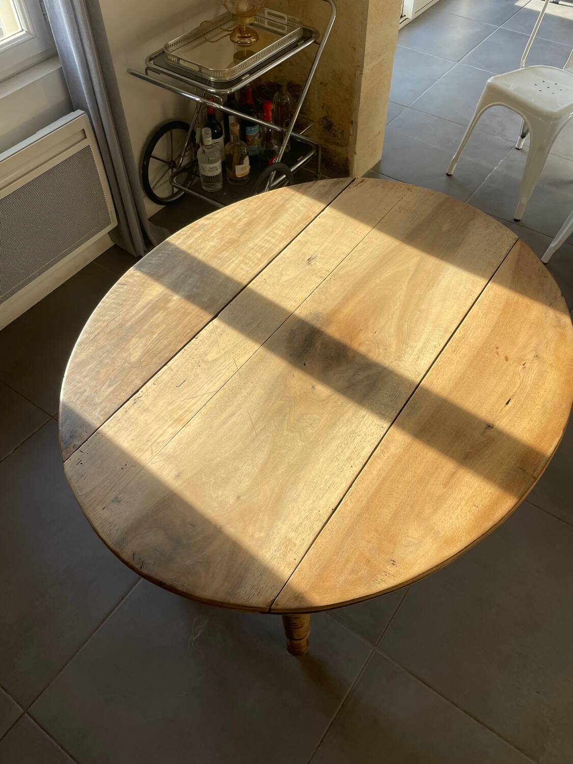 Oval wooden table with drop-leaf edges.
