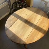 Oval wooden table with drop-leaf edges.