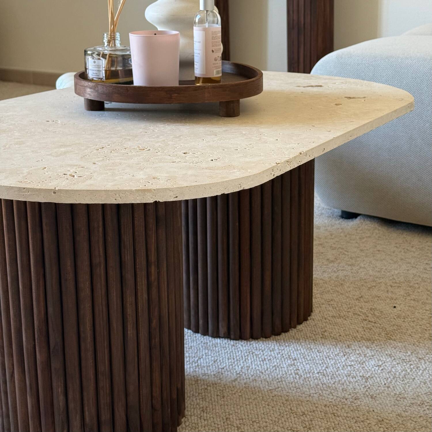 Oval coffee table in travertine and fluted wood.