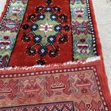 Vintage hand-knotted wool rug with polychrome decoration on a red, blue, green background 150 x 63 cm