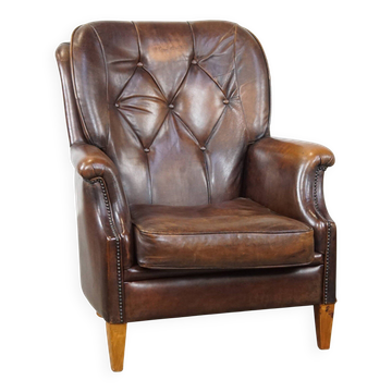 Fauteuil en peau de mouton vintage de couleur cognac foncé avec un siège confortable.