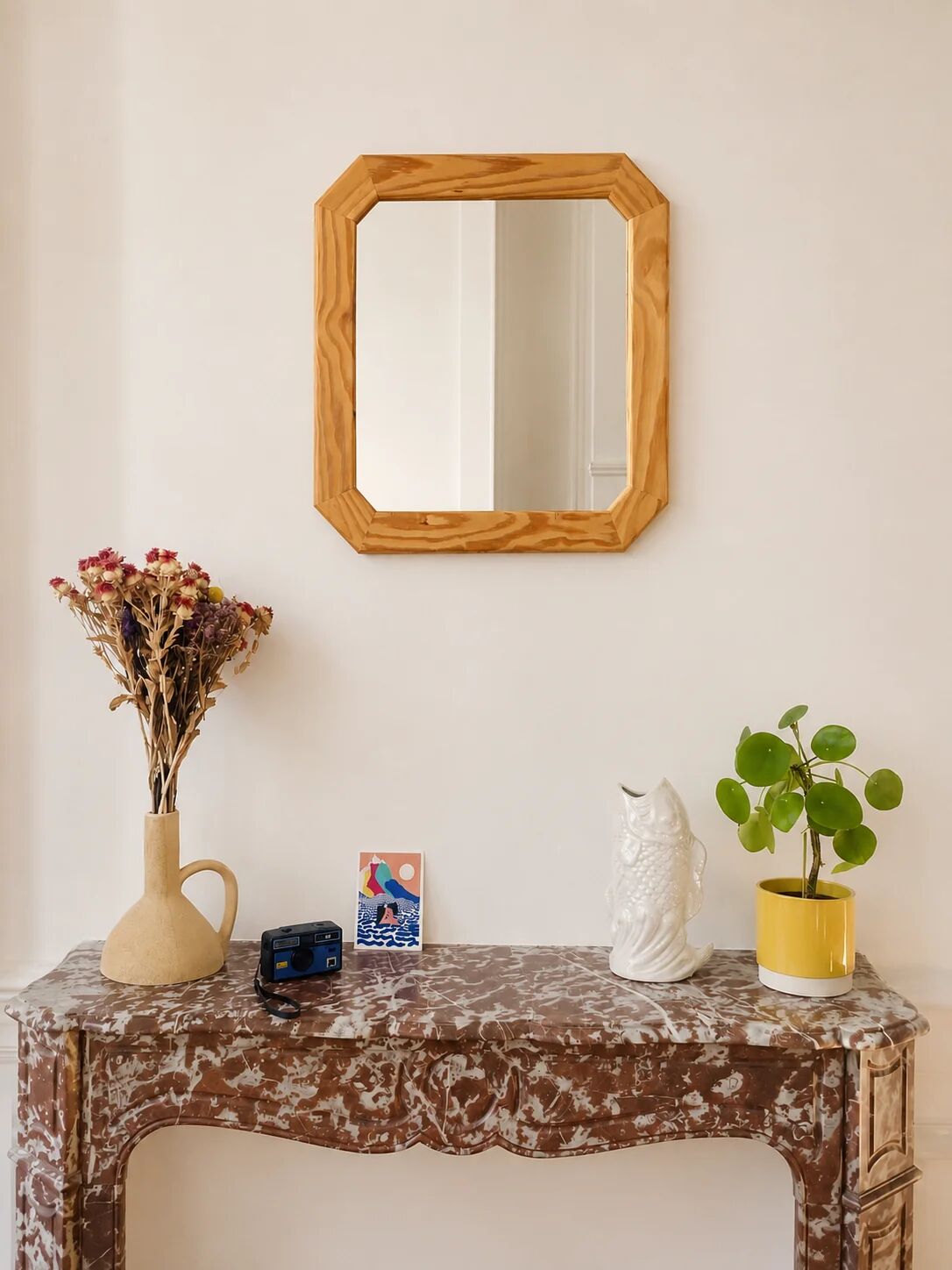 Octagonal mirror in light wood with grooves.