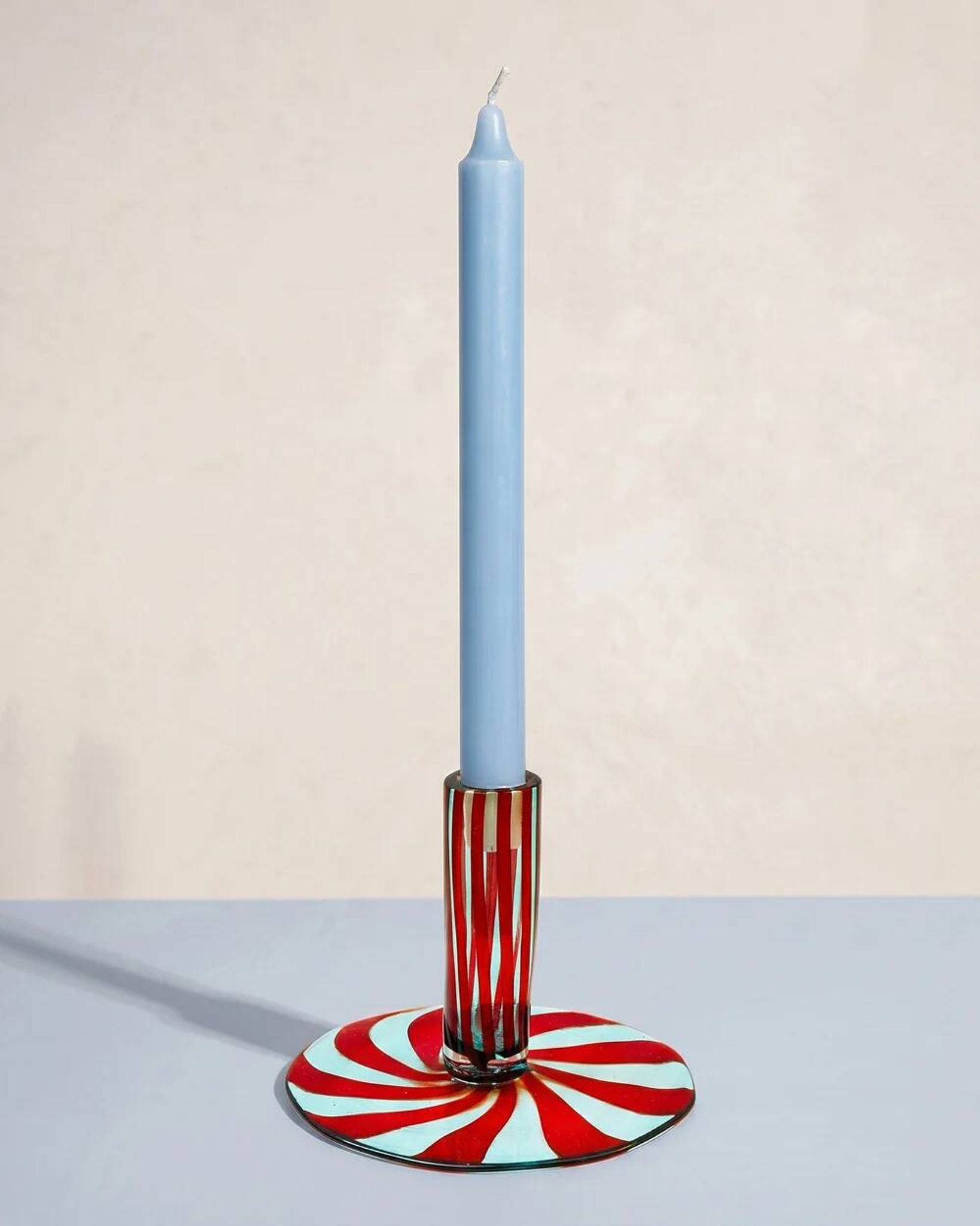 Murano glass candlestick with swirling red and blue ribbons.