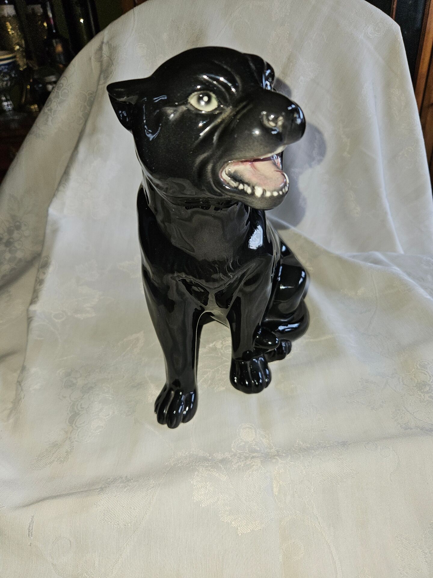 Statue of a roaring panther/leopard sitting in black glazed ceramic.