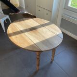 Oval wooden table with drop-leaf edges.