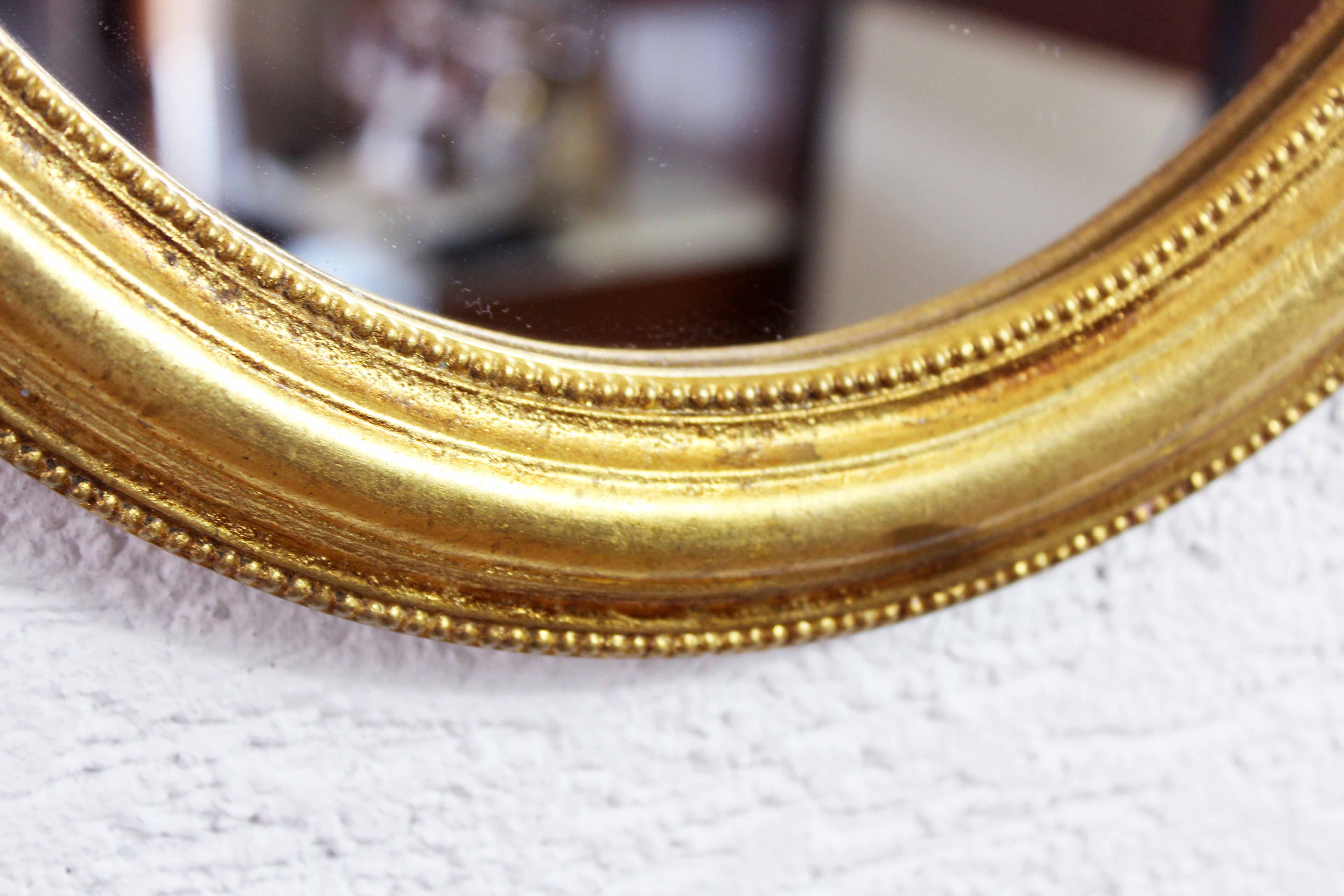 Golden oval mirror with leaf