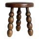 Small three-legged stool made of turned wood.
