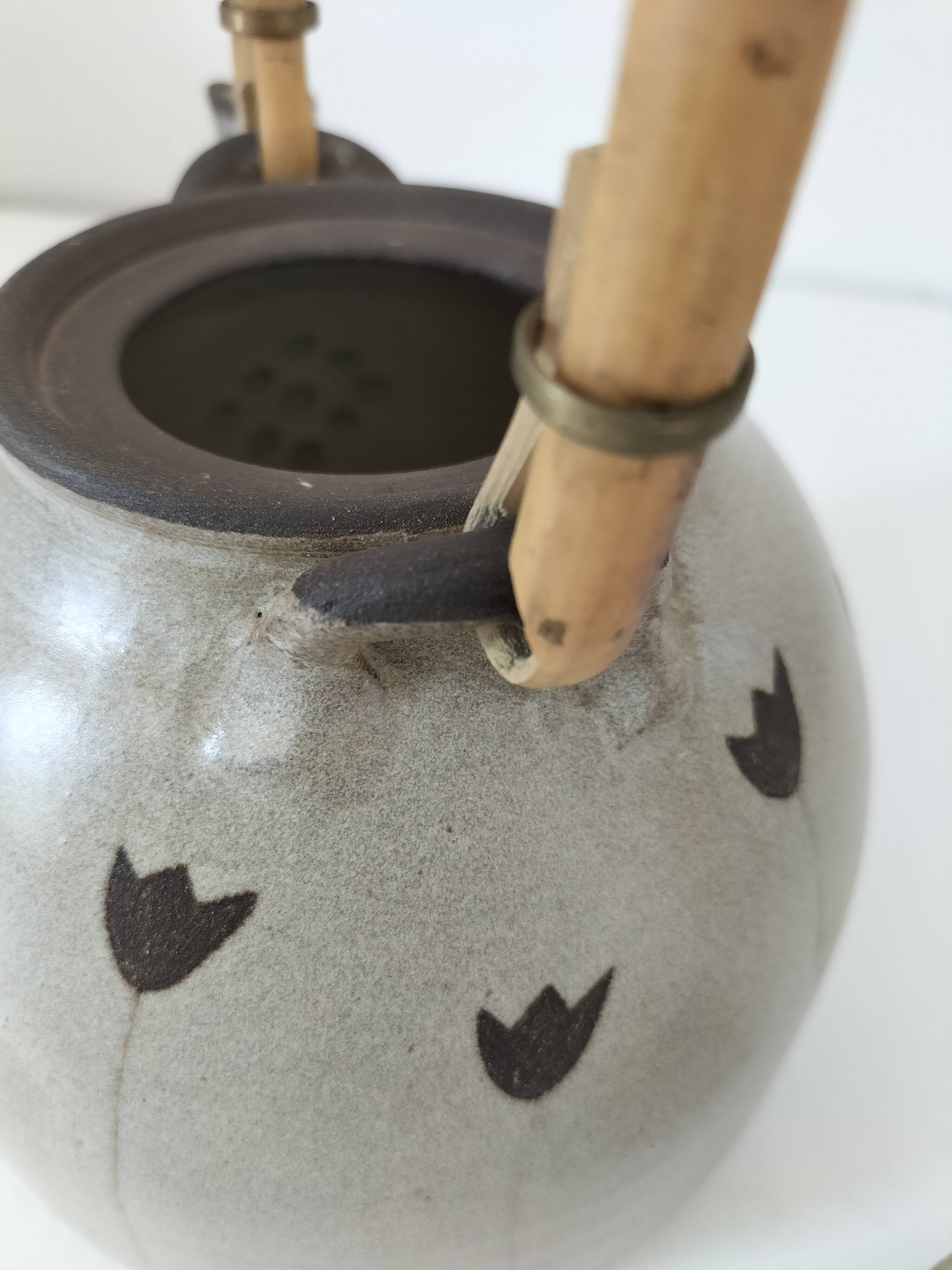 Beige stoneware teapot with stylized flowers and rattan handle