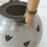 Beige stoneware teapot with stylized flowers and rattan handle