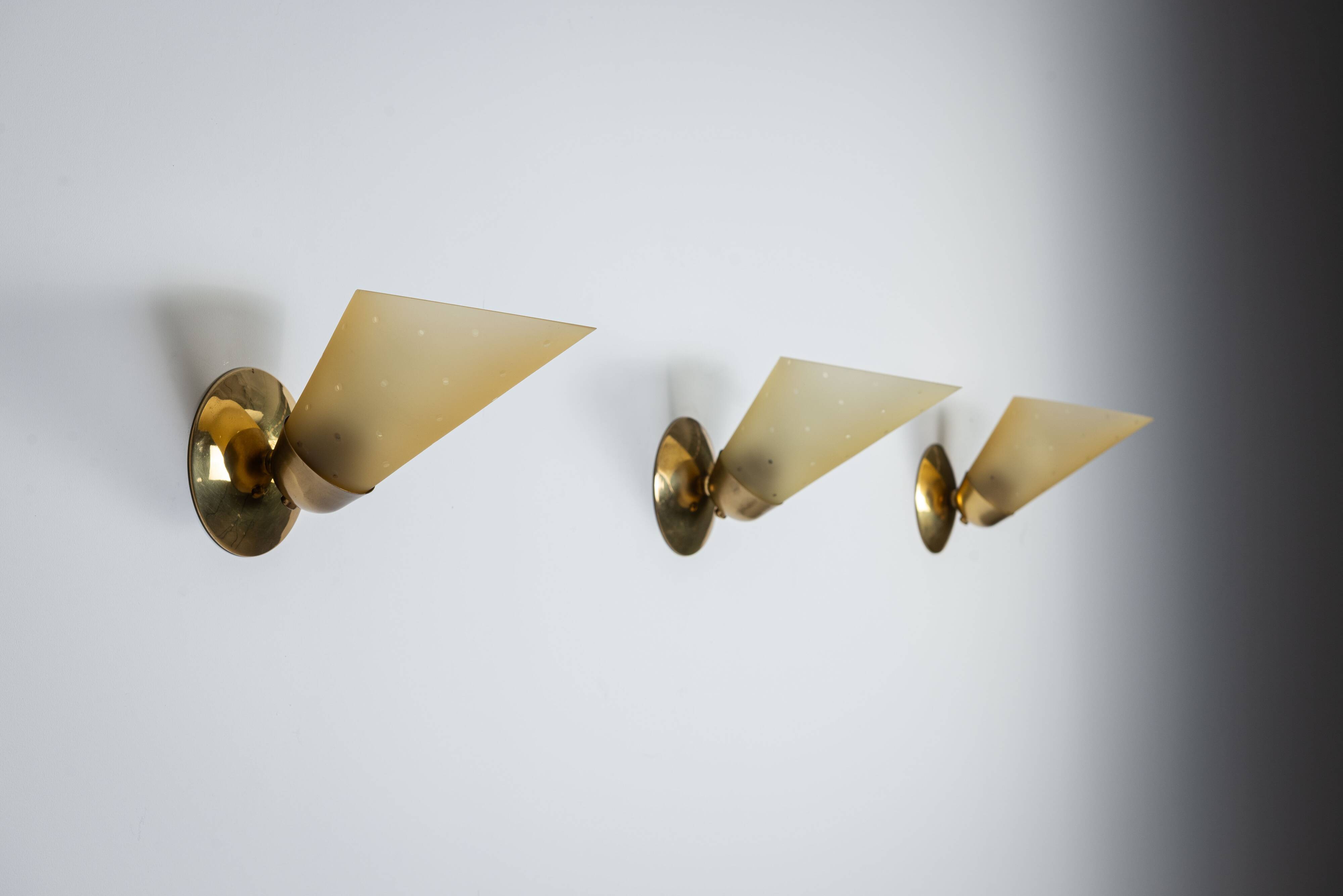 Set of three brass sconces with decorated yellow glass shades
