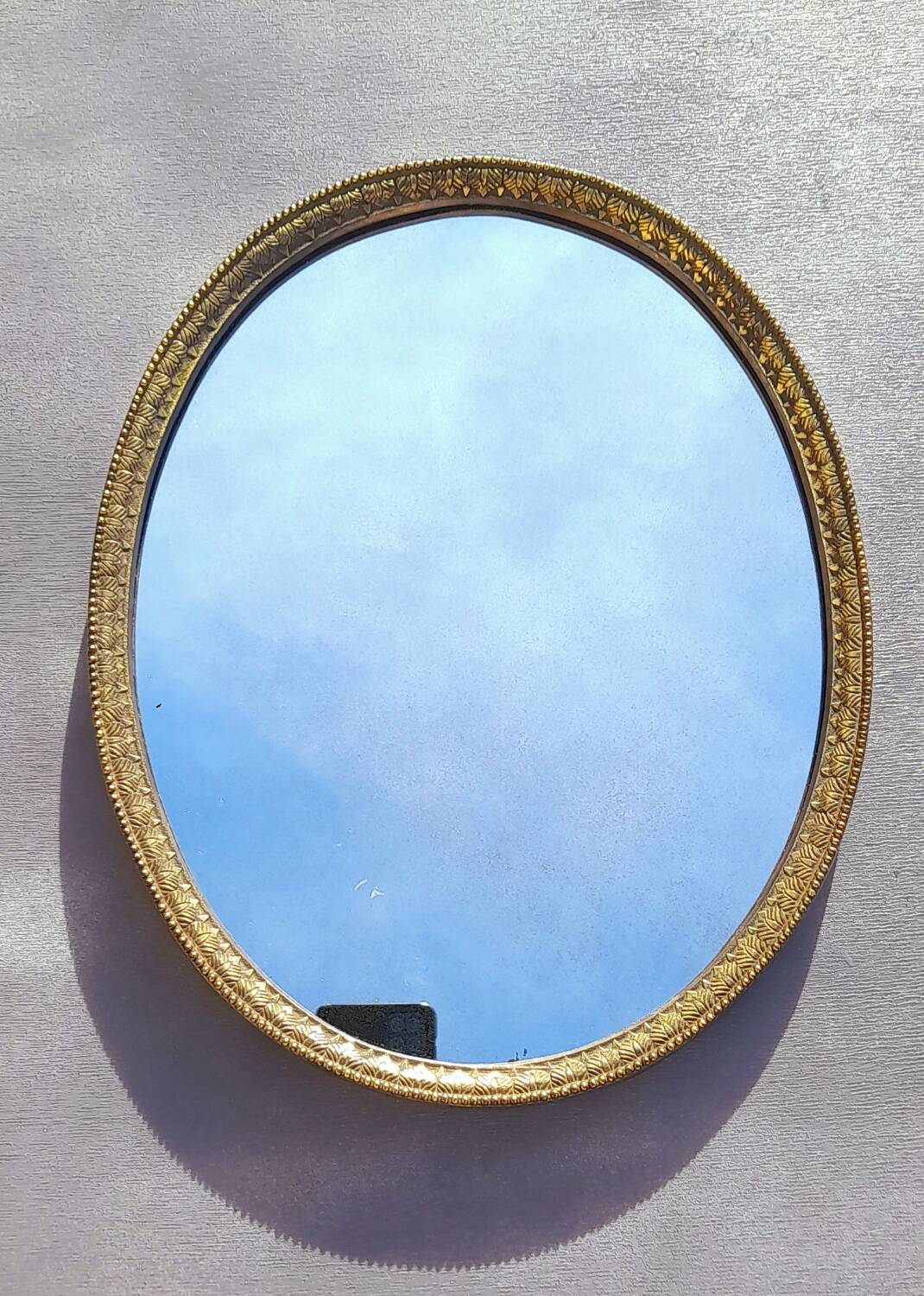 Oval mirror in gold metal