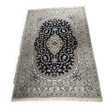 Tapis persan Nain noué à la main avec un motif floral bleu et blanc.