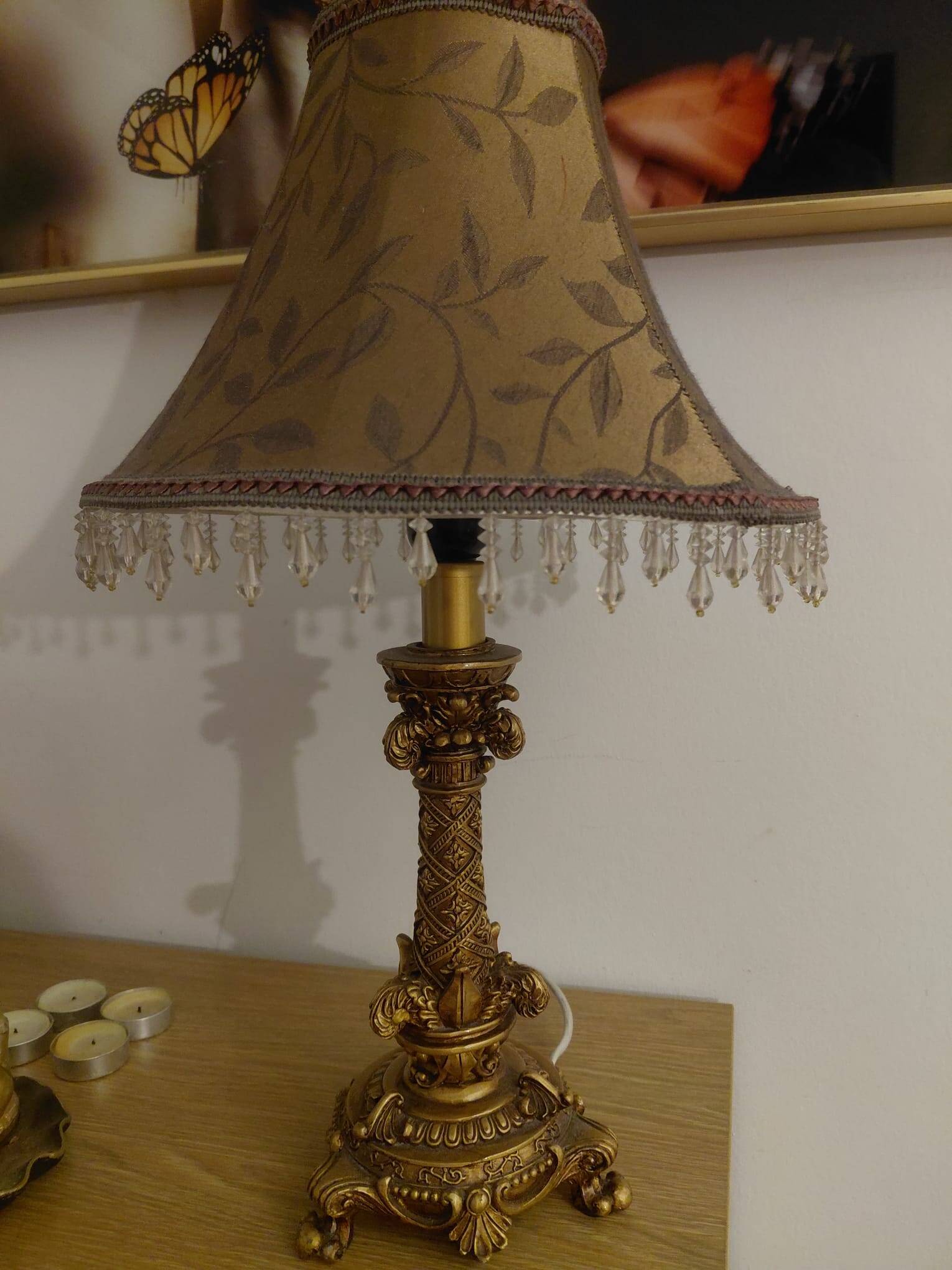 Golden baroque-style table lamp with a shade adorned with pendants.