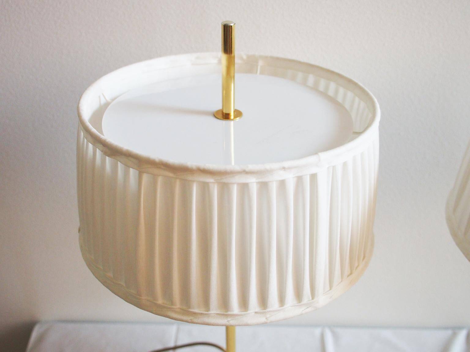 Paire de lampes de bureau suédoises en laiton avec des détails en cuir et des abat-jours blancs.